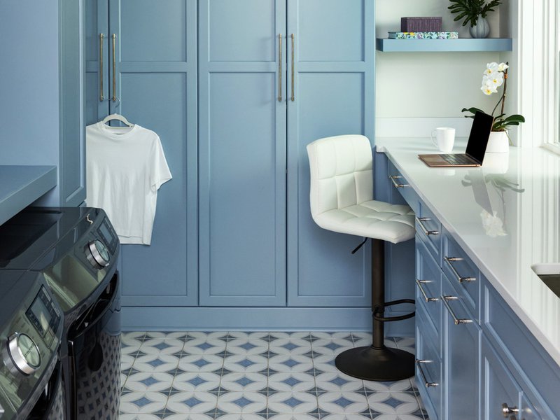 Laundry room with blue cabinets, shelves, and white counter tops.