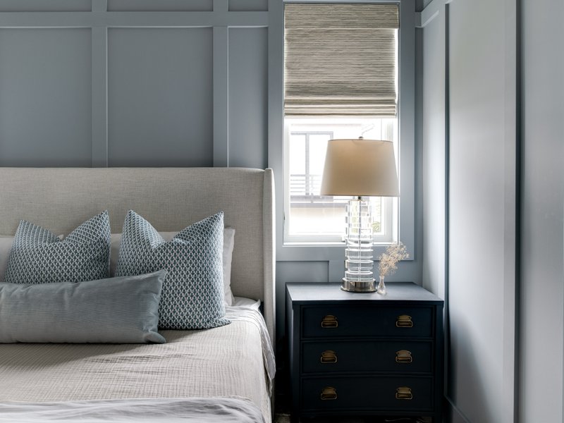 Bedroom with gray wall panels, a bed, and table lamp